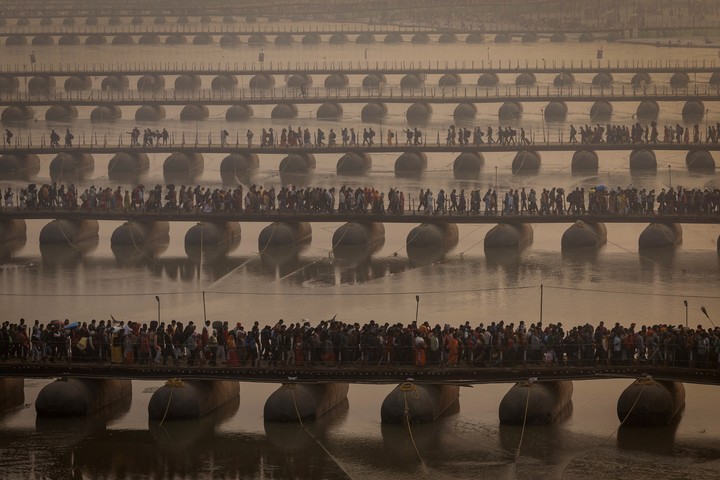 Los devotos cruzan el puente para bañarse en Sangam, donde se da la confluencia de los ríos Ganges y Yamuna. Foto: Reuters