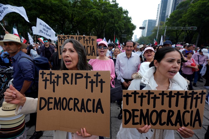 Manifestantes gritan consignas contra las primeras elecciones judiciales del país, mientras sostienen carteles con la leyenda "QEPD Democracia", durante una protesta junto al Ángel de la Independencia en la Ciudad de México. Foto AP