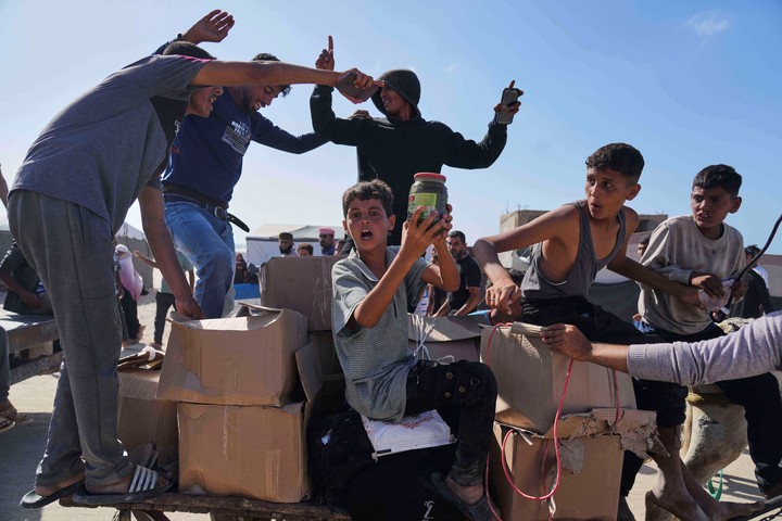 Palestinos llevan cajas con alimentos y paquetes de ayuda humanitaria entregados por la Fundación Humanitaria de Gaza, una organización respaldada por Estados Unidos y aprobada por Israel, en Rafah, sur de la Franja de Gaza. Foto AP