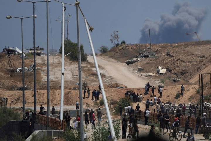 Tanques del ejército israelí se posicionan mientras se eleva el humo al fondo en el sur de Gaza, desde un centro de distribución de ayuda humanitaria operado por la Fundación Humanitaria de Gaza. Foto AP