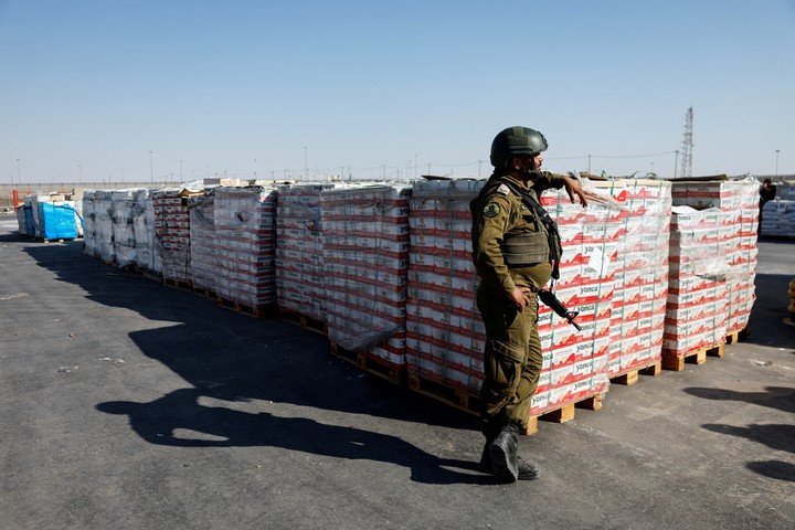 Un soldado israelí hace guardia junto a cargamentos de ayuda humanitaria para la población de Gaza, en la zona fronteriza de Kerem Shalom, este jueves. Foto: REUTERS 