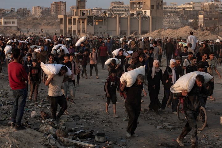 Palestinos desplazados cargan bolsas de harina donadas por organizaciones de ayuda, en Jabalia, en la Franja de Gaza. Foto: EFE  
