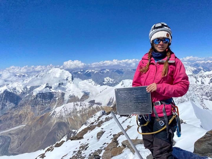 Nagovitsyna con una placa conmemorativa de su marido fallecido en alta montaña en 2021, a menos de 20 km de donde quedó atrapada ella. Foto captura redes