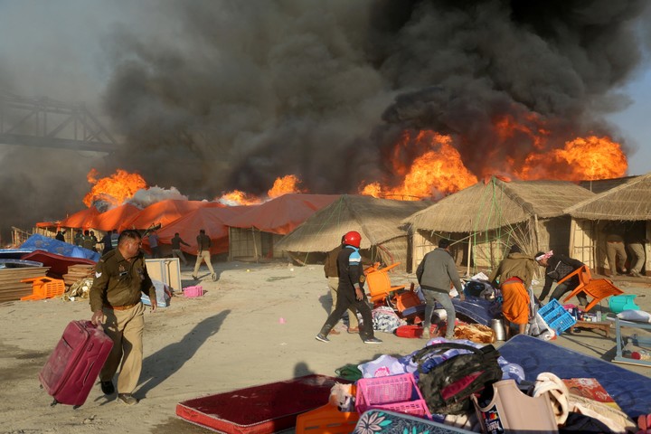 Police officers and volunteers salvage belongings of the devotees after a fire erupts in makeshift tents during the ongoing "Maha Kumbh Mela", or the Great Pitcher Festival, in Prayagraj, India, January 19, 2025. REUTERS/Stringer
